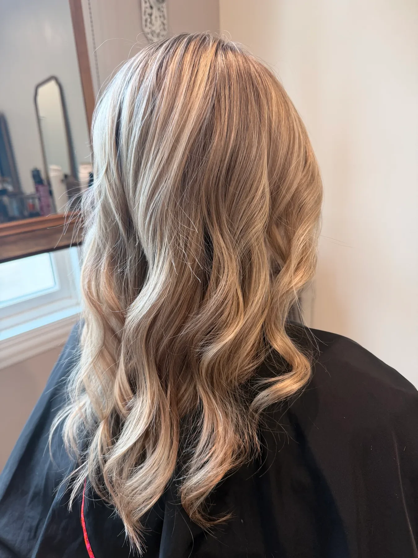 Dimensional blonde balayage styled in soft waves by Glow Salon & Spa