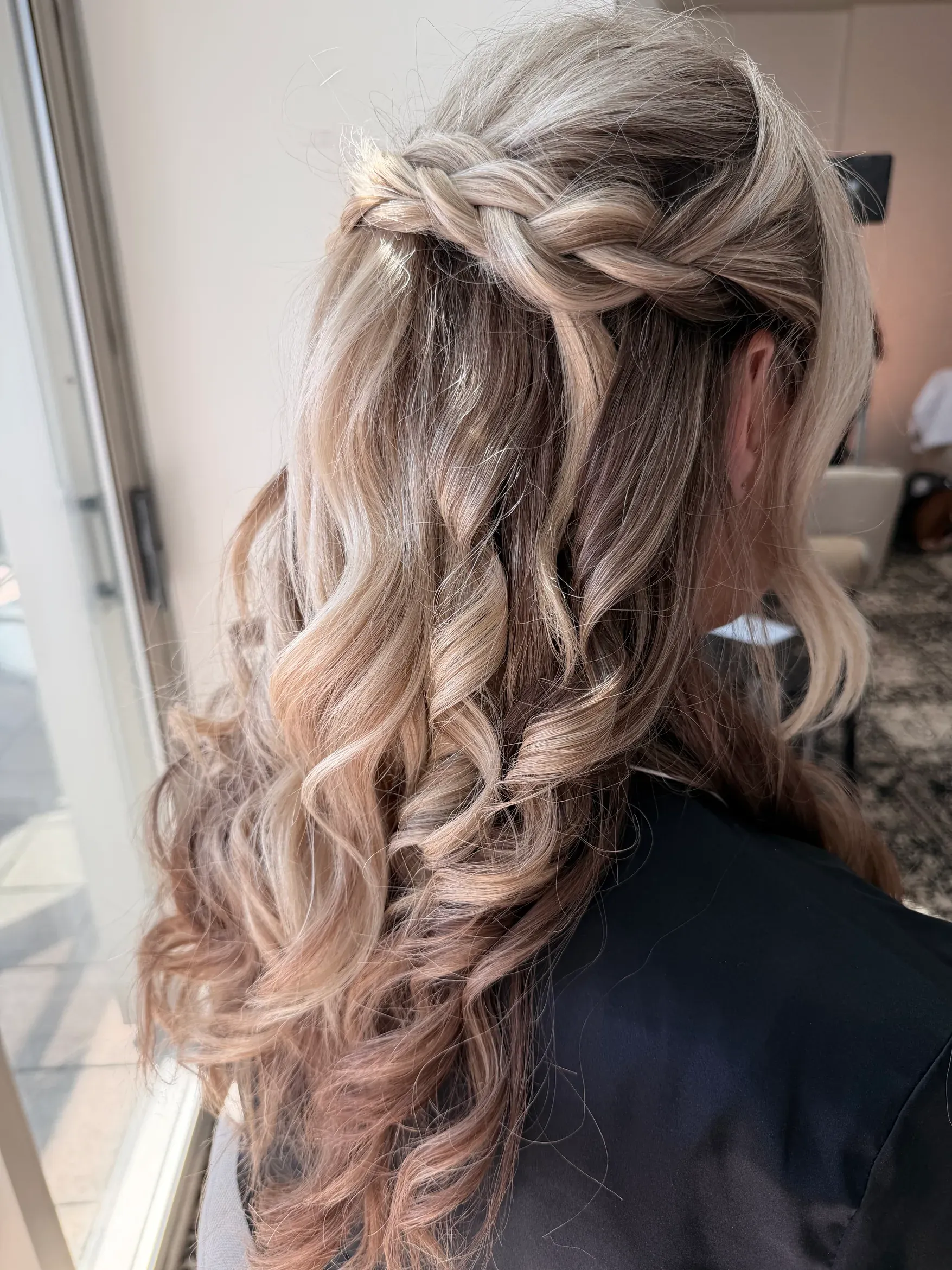 Loose braided bridal hairstyle with soft curls by Glow Salon & Spa