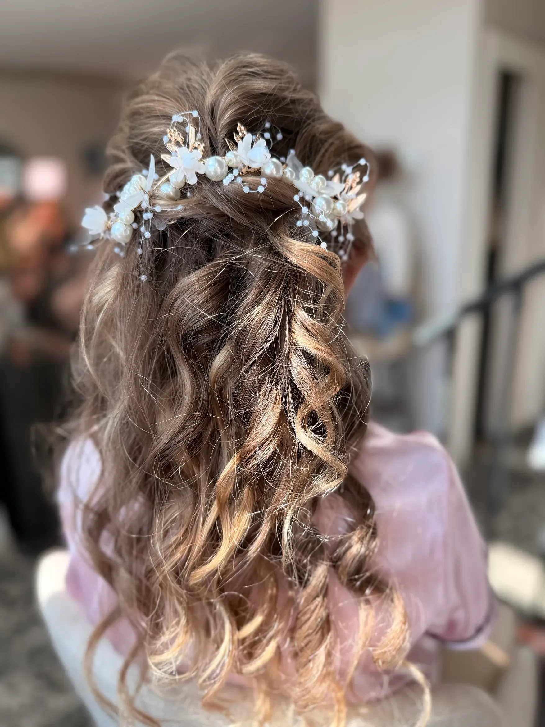 Wedding hairstyle with floral hairpiece and soft curls by Glow Salon & Spa